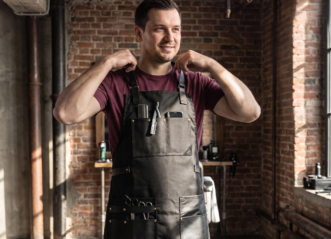 Barber wearing a protective cross-back apron while working in a modern barbershop